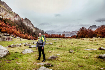 Portrait of smiling man hiking in field beneath mountain