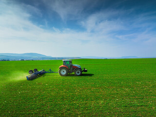 Tractor with a roller tillage on spring field. Aerial view of Soil rolling supports germination and...