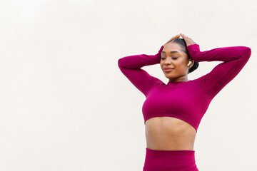 Joyful young black woman exercising on white background, using earpods