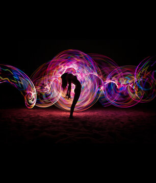 Silhouette of a woman posing by light on a beach at night