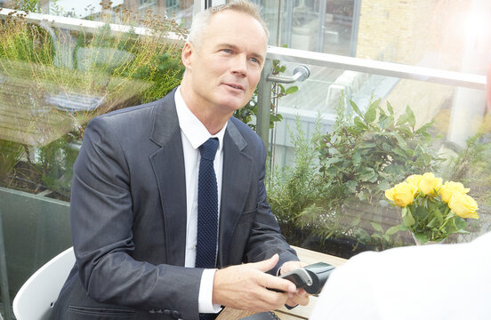 Businessman using EFTPOS machine at restaurant table