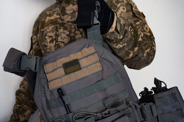 Ukrainian soldier in military pixel unform camouflage with grey bulletproof vest in one arm and...