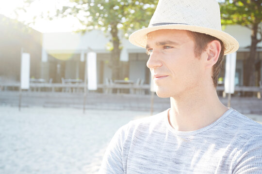 Young man wearing straw trilby hat on beach