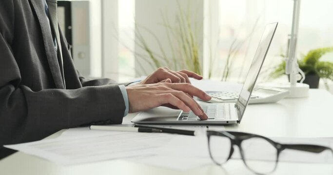 Skilled hands of an entrepreneur as he deftly types on his laptop and writes with a pen. He multitasks, efficiently managing digital tasks on his laptop and jotting down essential notes on paper.