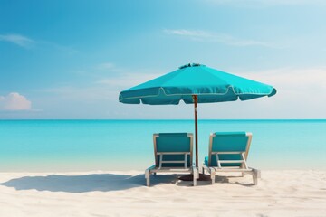 Two chaise longues under a sun umbrella stand on the beach on the ocean or sea coast, blue lagoon of a resort island or country. Dream vacation travel package