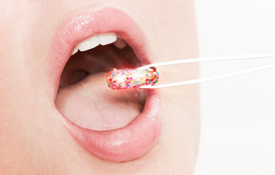 Lips of woman taking glitter capsule with tweezers