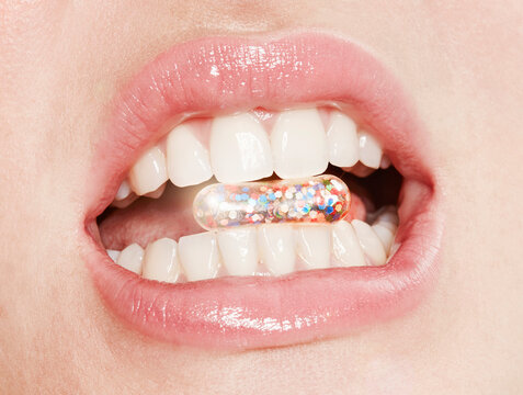 Lips of woman taking glitter capsule