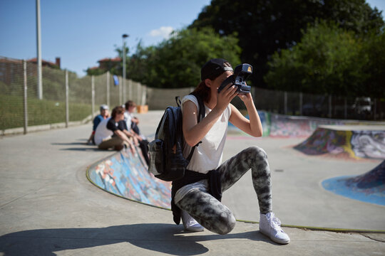 Teenage girl using polaroid camera at skatepark