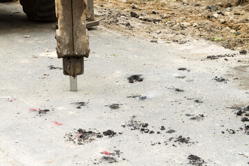 Large jackhammer making holes in pavement