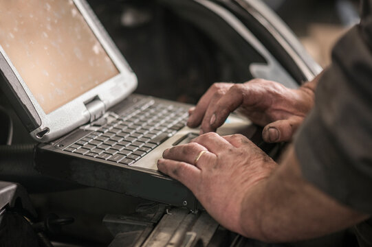 Hands of mechanic using laptop