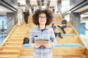 Young businessman with tablet PC by office staircase