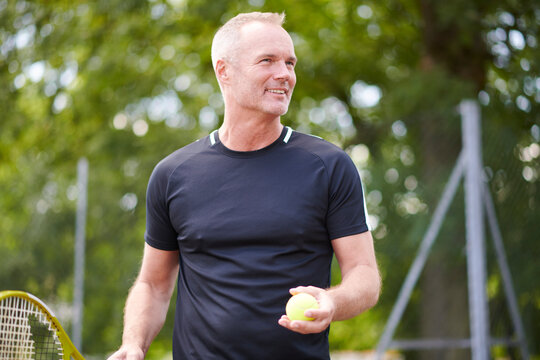 Mature man holding tennis racket and ball