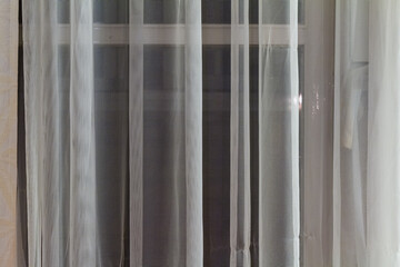 Thin translucent curtains hanging in a window