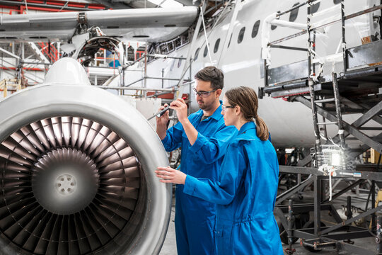 Man and woman working on airplane engine