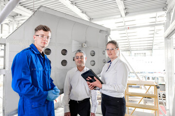 Workers with digital tablet in airplane hangar
