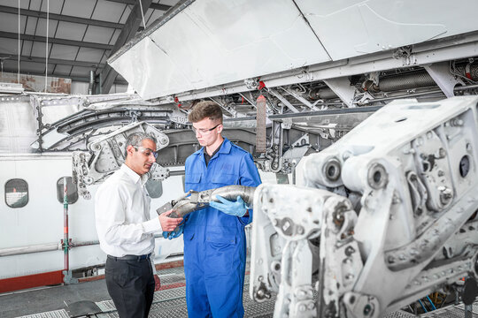 Men examining pipe in airplane hangar