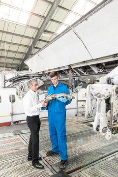 Men examining pipe in airplane hangar