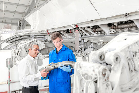 Men examining pipe in airplane hangar