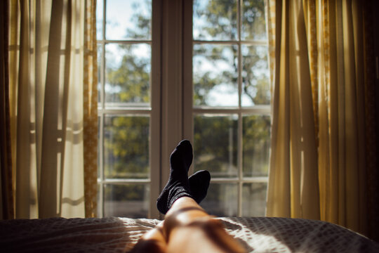 Feet of woman wearing black socks by window