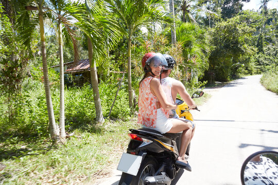 Young man and woman riding moped
