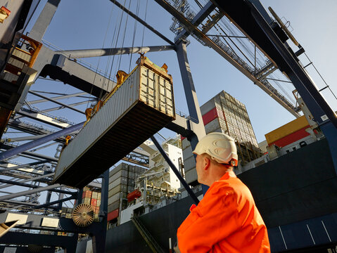 Dock worker watching cargo container being unloaded at Port of Felixstowe, England