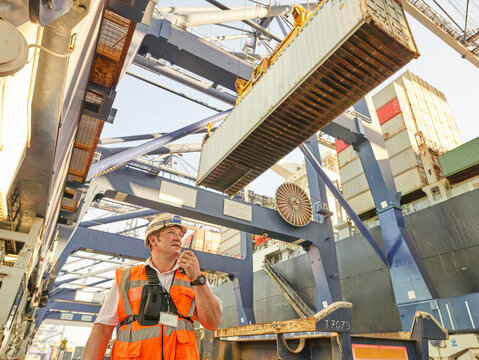 Dock manager communicating with crane driver to load cargo to lorry