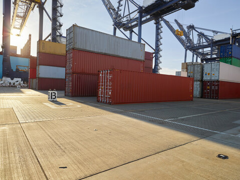 sunset at port, container stack empty cranes in background