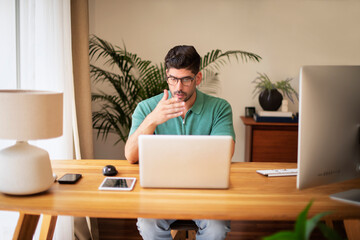 Confident businessman sitting at desk with laptop and working at home