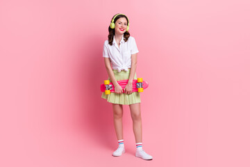 Obraz na płótnie Canvas Full length photo of adorable positive girl dressed white top enjoying songs rising penny board isolated pink color background