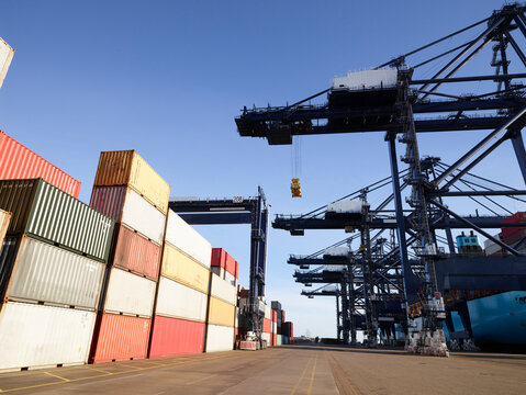 Cargo cranes and shipping containers against clear blue sky, Felixstowe, England.