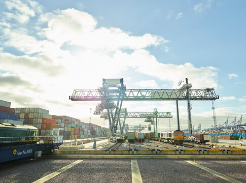 Cargo cranes and shipping containers in dockyard railway, Felixstowe, England.