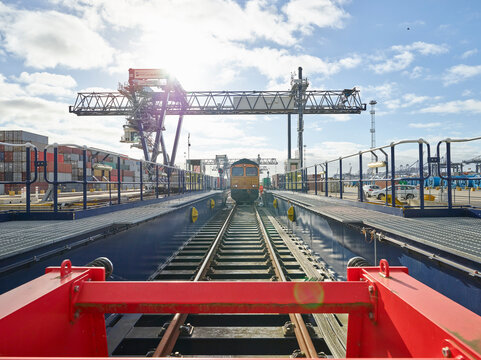 Railway buffer stop in dockyard with train in distance, Felixstowe, England.