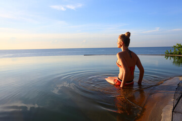 Young woman in swimming pool at sunset