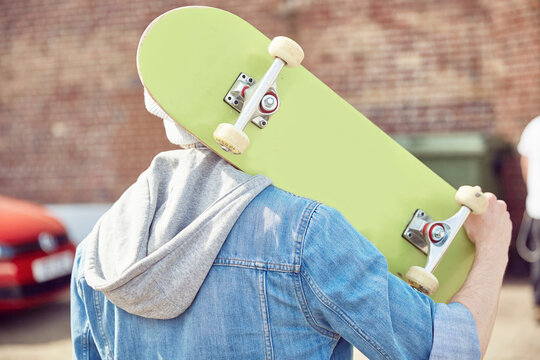 Rear view of teenage boy carrying skateboard