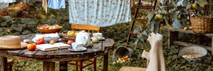 wooden table set for tea in the garden under an apple tree next to the ropes where the laundry is dried, cozy and comfortable autumn still life.