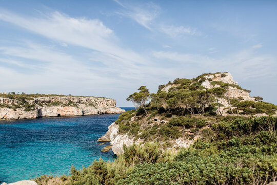 Tree covered cliffs by sea at Calo des Moro in Mallorca