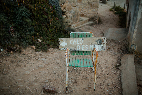 Rusted chair with a wooden sign at Calo des Moro in Mallorca