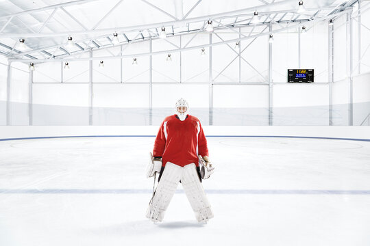Ice hockey goalkeeper wearing red uniform at an ice rink
