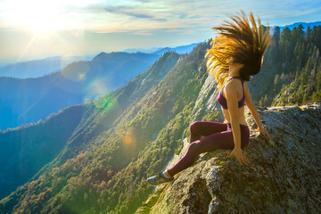 Young woman tossing her hair on a mountain rock - Powered by Adobe