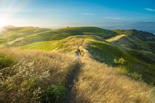 Young woman in grass on hill with stool and flowers