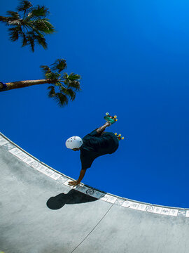 Man in helmet roller skating in bowl at skatepark