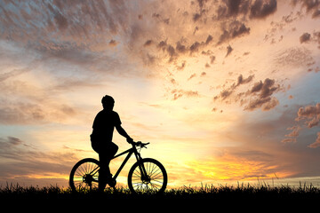 Obraz na płótnie Canvas Silhouette of cyclist exercising in the meadow in the evening, fitness health care concept