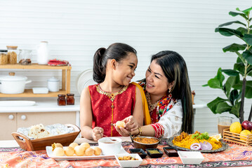 an Indian family, mother and daughter in the kitchen They happy together while eating Indian food,...