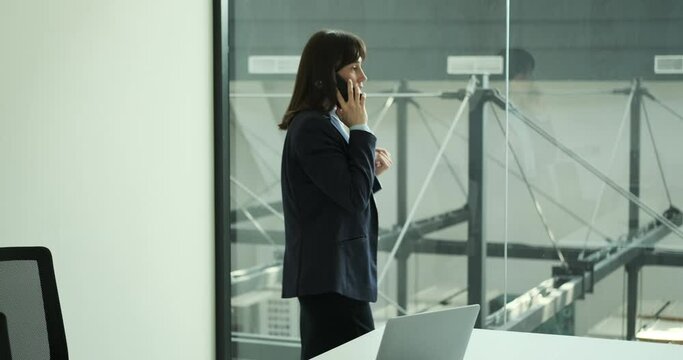 Attractive female entrepreneur as she confidently engages in business negotiations over the phone in office. With a assertive demeanor, she navigates the conversation with tact and professionalism.