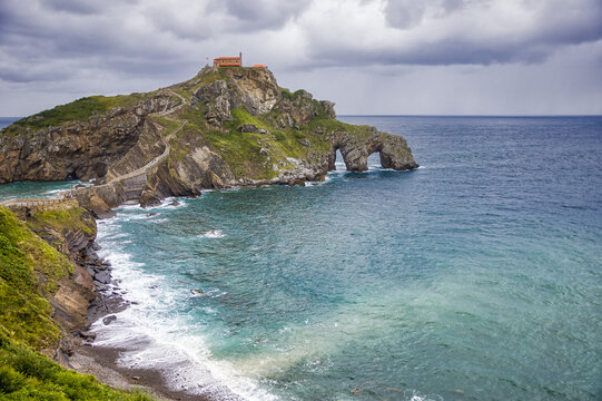 view of gaztelugatxe island with cloudy dramatic sky and stormy weather