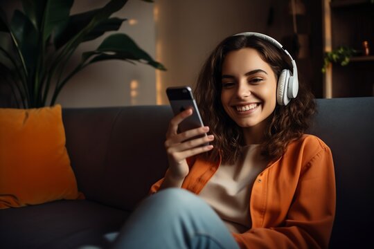 Woman With A Credit Card And A Phone On The Sofa At Home And Headphones