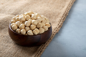 Top view of a bowl full of peeled hazelnuts  on burlap sack
