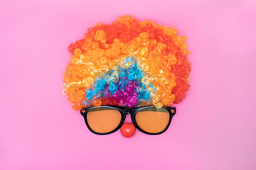 Funny Party concept face formed with glasses lens. Rainbow Clown Wig Set and red clown nose like a...