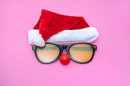 Funny Christmas Party concept face formed with sunglasses and a Santa hat. red clown nose like a face, Cosplay Festive Background