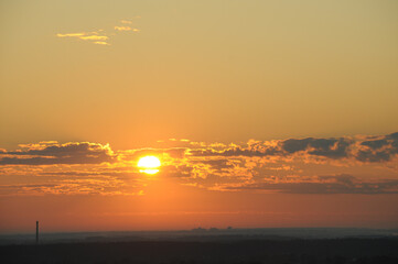 Early morning on a hot day, we see the golden sun in broken clouds.